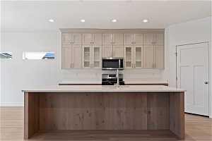Kitchen with gas range oven, stove, light hardwood / wood-style flooring, and a kitchen island with sink
