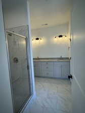 Bathroom with tile patterned floors, a textured ceiling, walk in shower, and double vanity