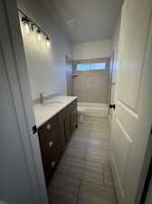 Full bathroom with vanity, tiled shower / bath, tile patterned flooring, and toilet