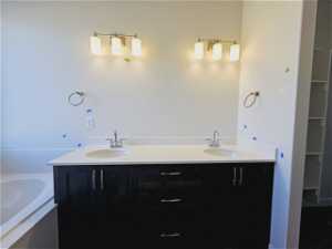 Bathroom with tiled bath and dual bowl vanity