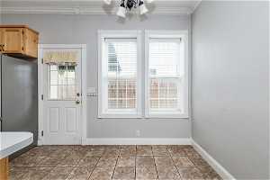 Doorway to outside featuring light tile flooring and crown molding