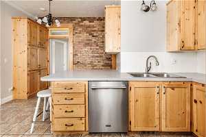 Kitchen with light tile floors, sink, dishwasher, tasteful backsplash, and pendant lighting