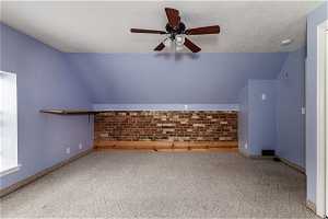 Bonus room featuring vaulted ceiling, ceiling fan, carpet flooring, and a textured ceiling