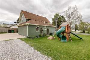 Back of house with a playground, a yard, and central air condition unit