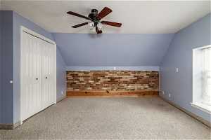 Bonus room featuring vaulted ceiling, a wealth of natural light, ceiling fan, and carpet flooring
