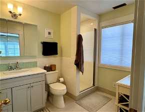 Master Bathroom featuring vanity with cabinet space, a shower with door, toilet, and tile floors