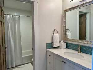 Full bathroom featuring backsplash, vanity, toilet, and shower / tub combo with curtain