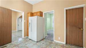 Kitchen featuring white refrigerator with ice dispenser and light tile floors