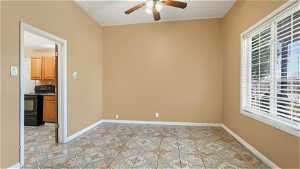 Empty room with ceiling fan and light tile floors