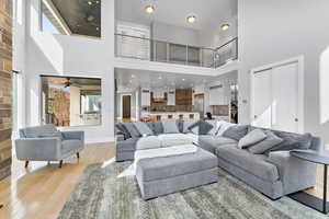 Living room with light wood-type flooring, a high ceiling, and ceiling fan