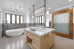 Interior space featuring vanity, a tub, a notable chandelier, and tile floors