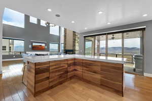 Kitchen featuring light wood-type flooring, a stone fireplace, and plenty of natural light