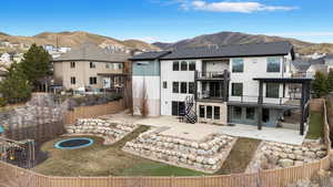 Rear view of property featuring a patio, a trampoline, a balcony, and a mountain view