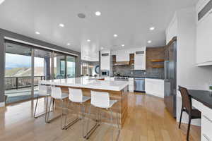 Kitchen with white cabinetry, a center island, a breakfast bar, built in appliances, and backsplash