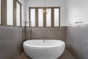 Bathroom with a bath to relax in, tile floors, and tile walls