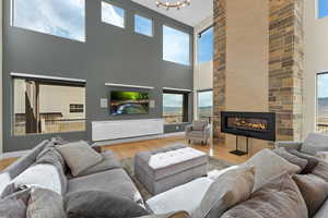 Living room featuring a large fireplace, an inviting chandelier, a high ceiling, and light hardwood / wood-style flooring