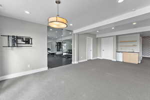 Unfurnished living room featuring sink and dark colored carpet