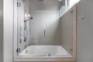 Bathroom with shower / bath combination with glass door and toilet