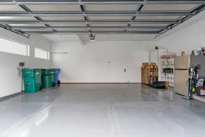 Garage featuring stainless steel fridge and a garage door opener