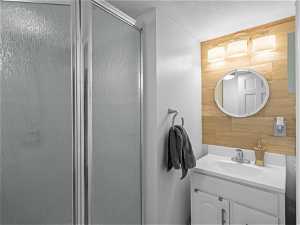 Bathroom with walk in shower, wooden walls, and large vanity
