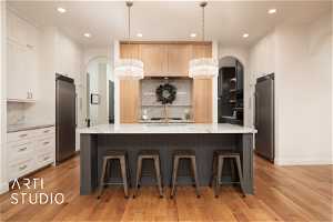Kitchen featuring stainless steel refrigerator, tasteful backsplash, a chandelier, and pendant lighting