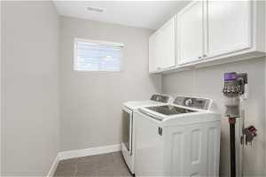 Laundry area with cabinets, light tile floors, and washer and dryer