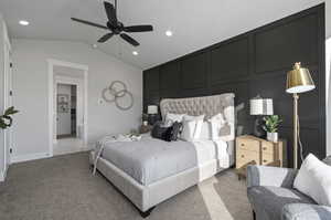 Carpeted bedroom featuring vaulted ceiling, ensuite bath, and ceiling fan