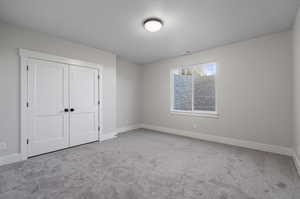 Unfurnished bedroom featuring light carpet and a closet