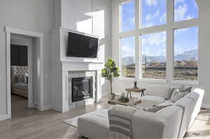 Living room with light hardwood / wood-style flooring, a mountain view, and a towering ceiling