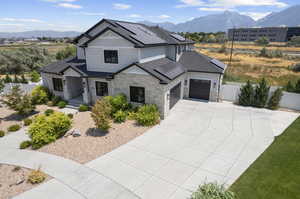 View of front of house featuring a garage, a mountain view, and solar panels