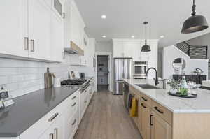 Kitchen with sink, light stone countertops, backsplash, light hardwood / wood-style floors, and white cabinetry