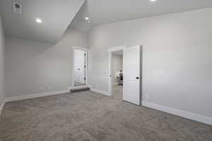 Unfurnished bedroom with lofted ceiling and light carpet