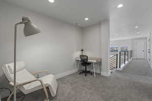 Office space with a textured ceiling and light colored carpet