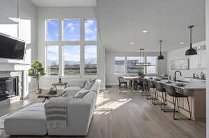 Living room with light hardwood / wood-style flooring, a towering ceiling, sink, and a high end fireplace