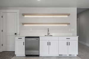 Bar featuring light carpet, white cabinetry, sink, and dishwasher