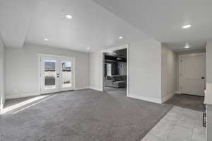 Unfurnished living room featuring light colored carpet, french doors, and a textured ceiling