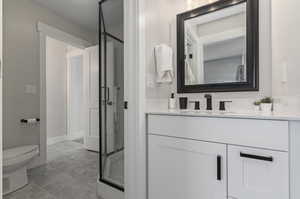 Bathroom with an enclosed shower, toilet, tile flooring, and vanity with extensive cabinet space