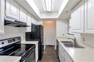 Kitchen with dark tile flooring, white cabinets, appliances with stainless steel finishes, and sink