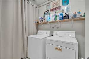 Washroom with washing machine and dryer. Utility room behind curtain