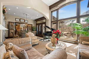 Carpeted living room featuring a towering ceiling, a chandelier, and french doors