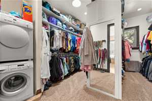 Spacious closet with light colored carpet and stacked washer / drying machine