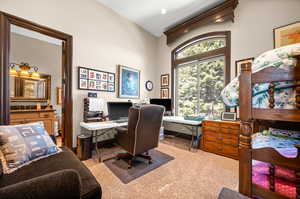 Office space with vaulted ceiling and light colored carpet