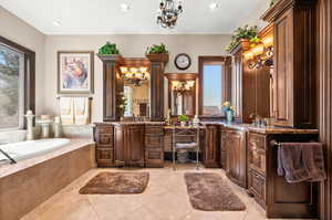 Bathroom with vanity, tiled tub, tile floors, and a chandelier