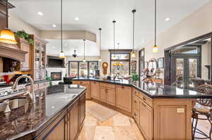 Kitchen featuring a breakfast bar area, pendant lighting, an island with sink, and a healthy amount of sunlight