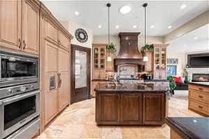 Kitchen featuring hanging light fixtures, light tile flooring, appliances with stainless steel finishes, and custom exhaust hood