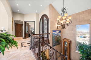 Hallway featuring tile walls, an inviting chandelier, and light tile flooring