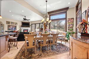 Tiled dining space featuring ceiling fan with notable chandelier and a healthy amount of sunlight