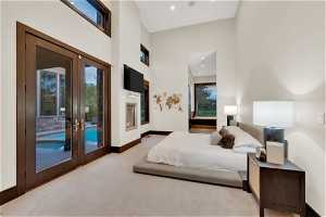 Bedroom with a high ceiling, light colored carpet, access to exterior, and french doors