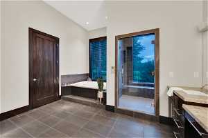 Bathroom featuring shower with separate bathtub, vanity, and tile floors