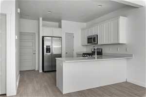 Kitchen with light wood-type flooring, white cabinets, appliances with stainless steel finishes, and sink